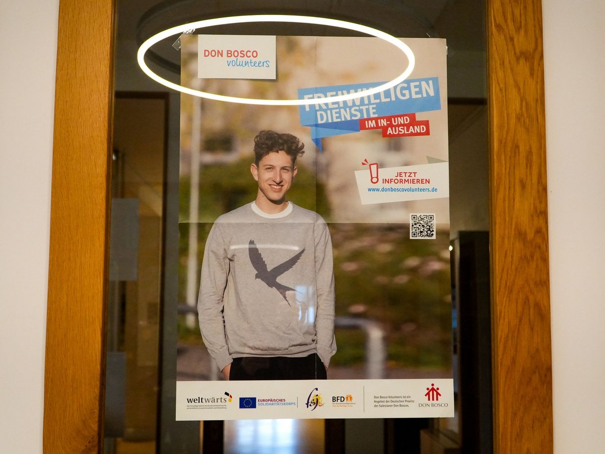 Plakat: Don Bosco Volunteers, ein lächelnder junger Mann, wirbt für Freiwilligendienste im In- und Ausland.