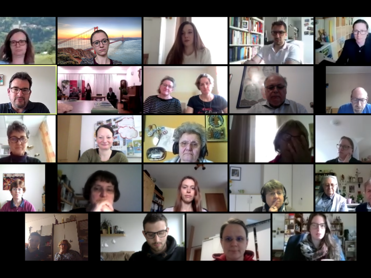 Ein Raster von 25 Personen, die an einer Videokonferenz teilnehmen, zeigt verschiedene Personen in unterschiedlichen Innenräumen.