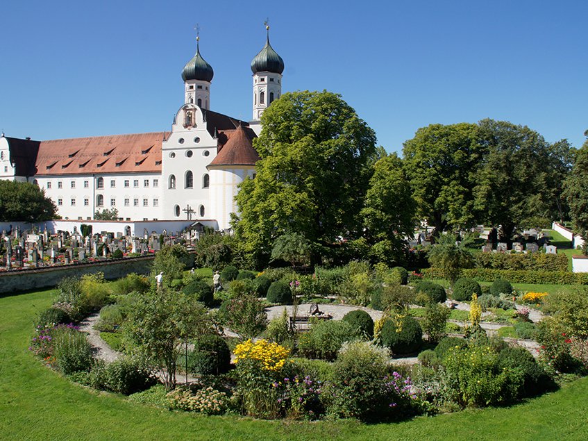 Kloster Andechs, ein historisches bayerisches Kloster mit zwei Zwiebeltürmen, umgeben von einem Friedhof und Garten.