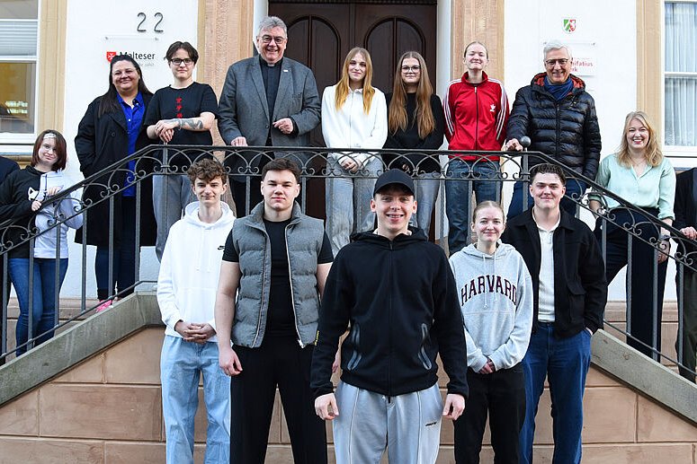 Eine Gruppe junger Menschen und Erwachsener vor und auf einer Treppe.