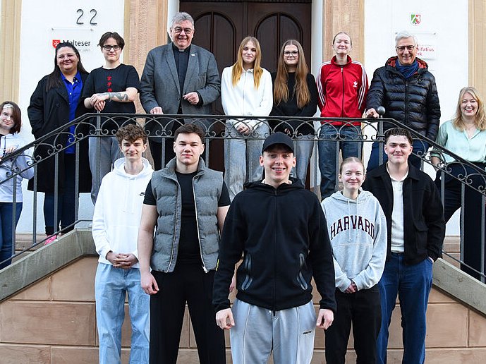 Eine Gruppe junger Menschen und Erwachsener vor und auf einer Treppe.