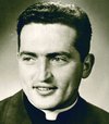 Halbporträt eines lächelnden jungen Priesters mit dunklem Haar und Kollar in Sepia-Tönen.