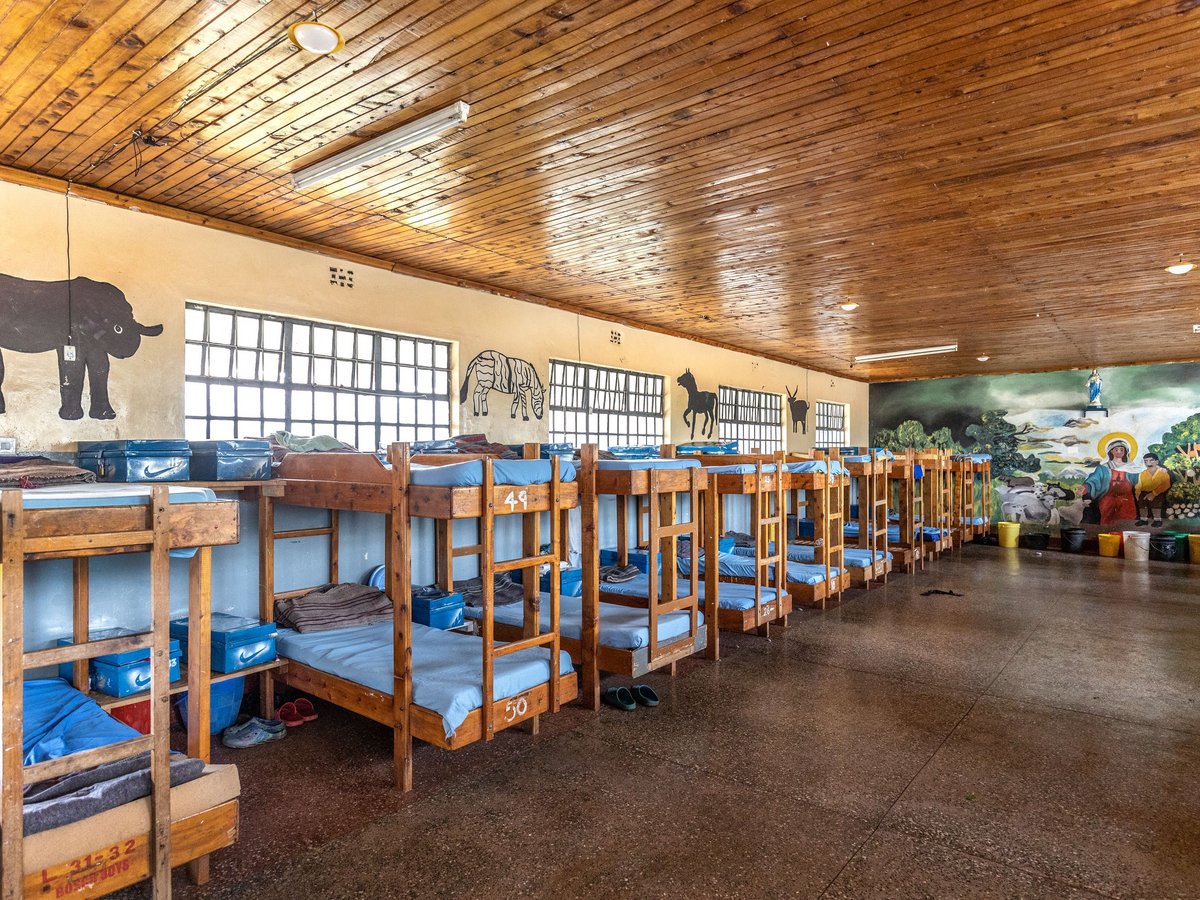 Innenansicht eines großen Schlafsaals mit Etagenbetten, Tiermalereien an den Wänden und einem religiösen Wandbild.