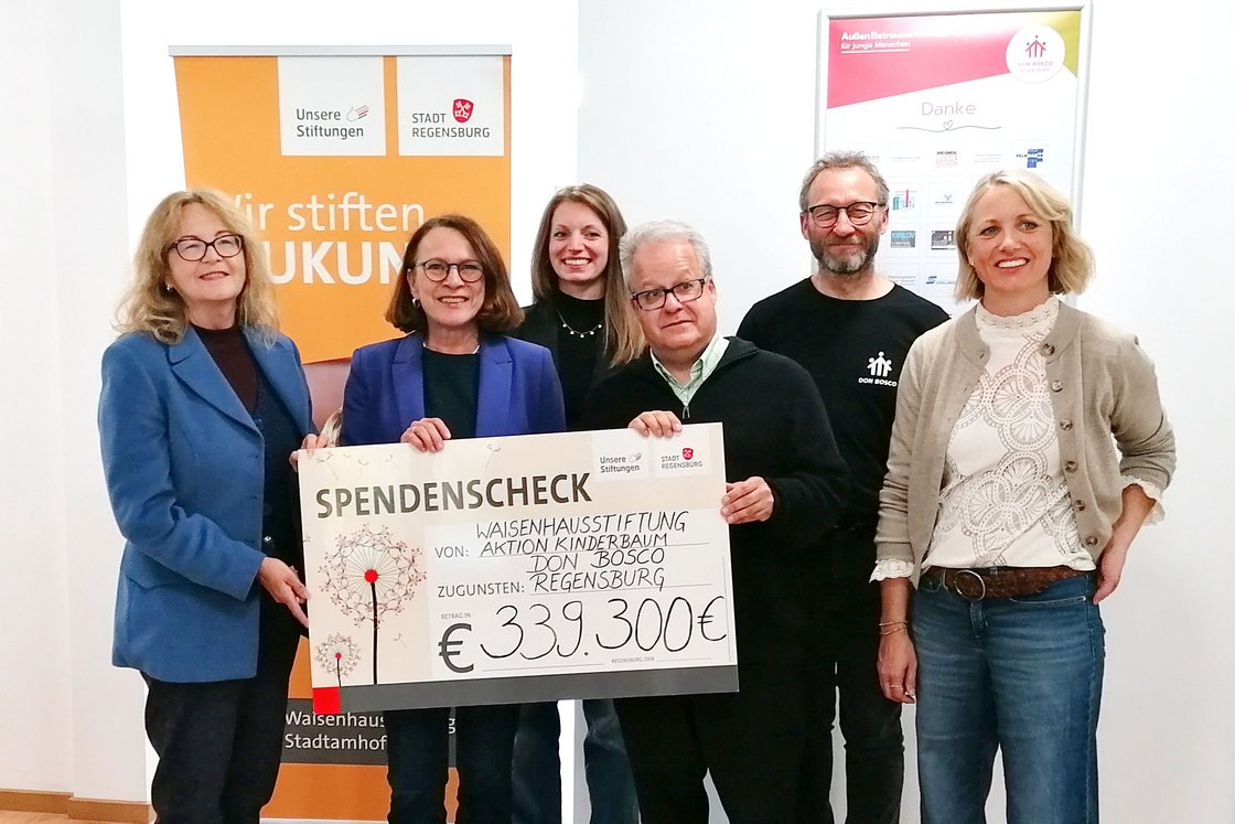 Sechs Personen halten Spendenscheck über 339.300 € von Waisenhausstiftung, Aktion Kinderbaum, Don Bosco, zugunsten Regensburg.