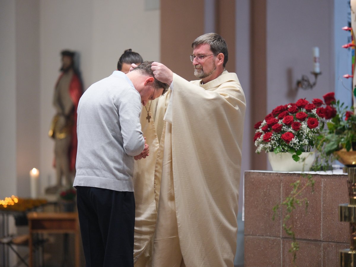 Priester legt einem Mann in der Kirche die Hände zur Segnung auf.