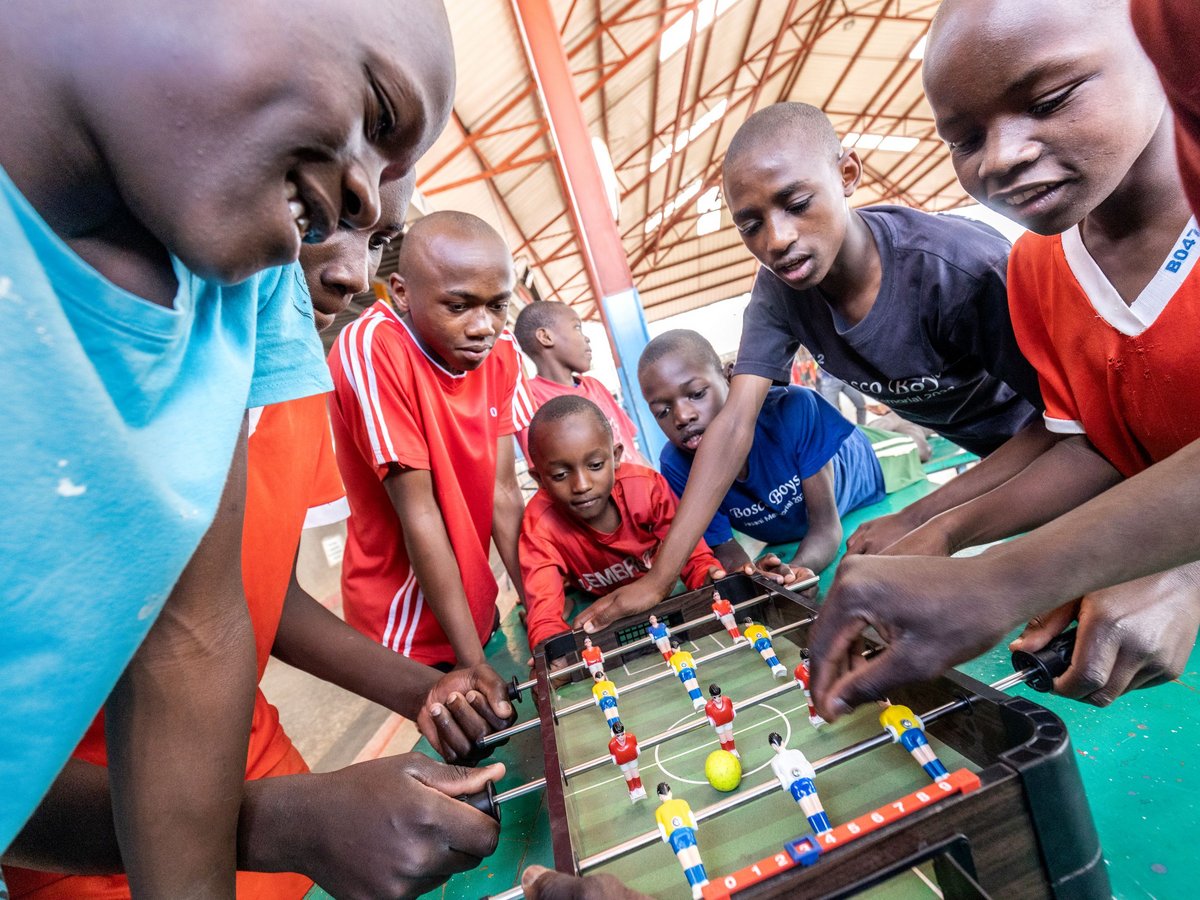 Afrikanische Kinder spielen Tischfußball, zeigen Engagement und Freude. Mehrere Jungen verschiedenen Alters konzentrieren sich auf das Spiel.