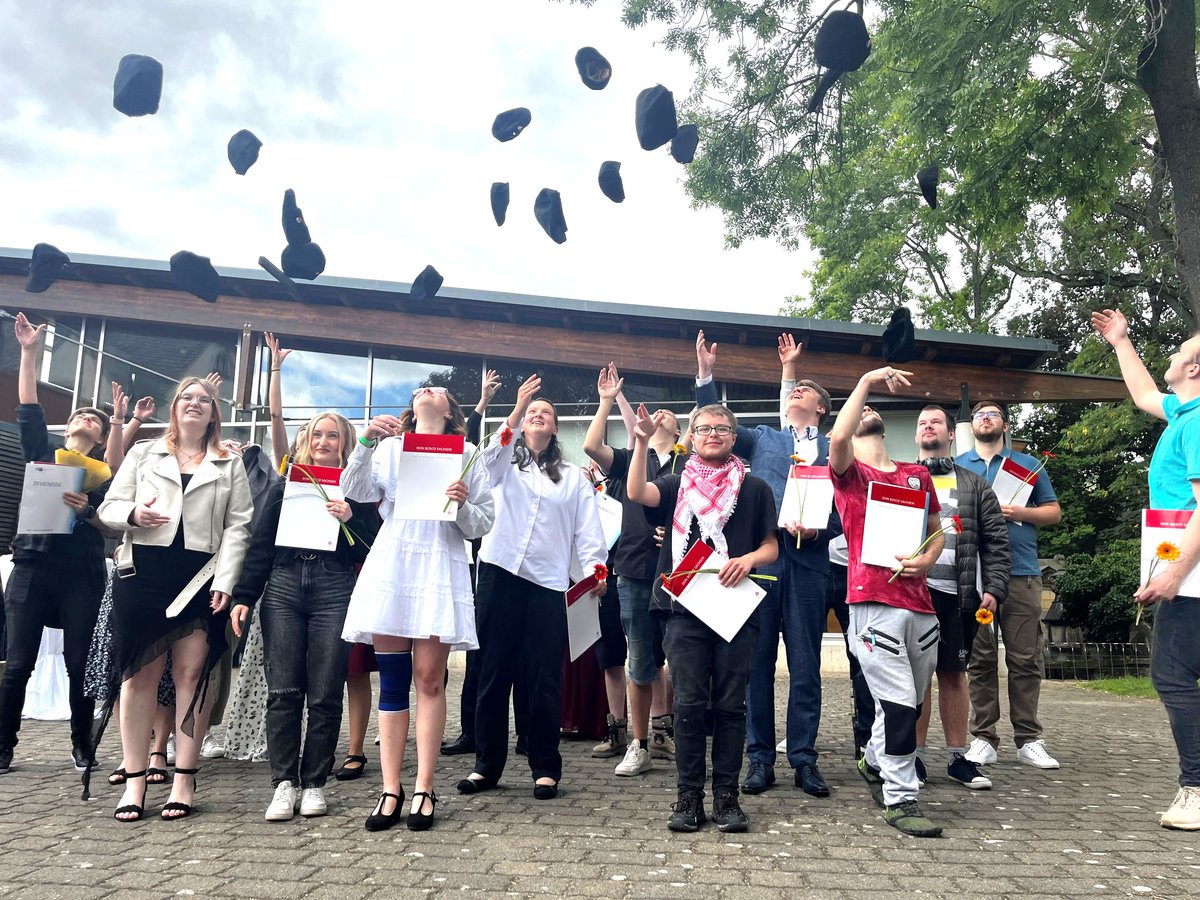 Glückliche Absolventen werfen ihre Hüte in die Luft, halten Zeugnisse und Blumen und feiern ihren erfolgreichen Abschluss im Freien.