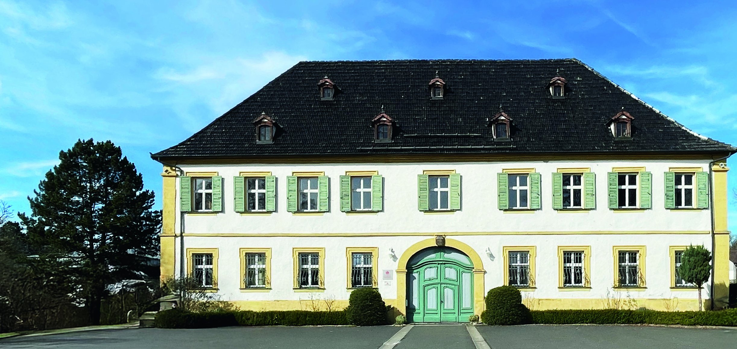 Außenansicht weißes Haus mit schwarzen Dach und Asphalt davor