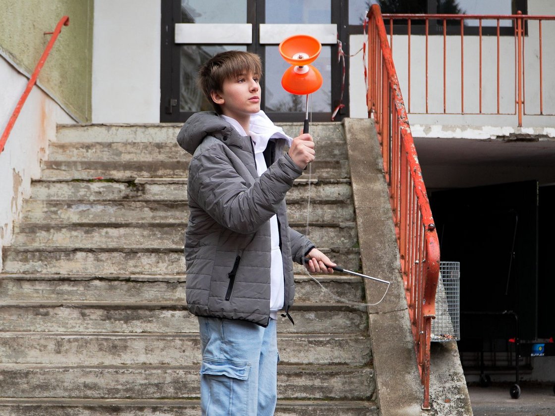 Ein Junge spielt vor einer Treppe mit einem Diabolo.