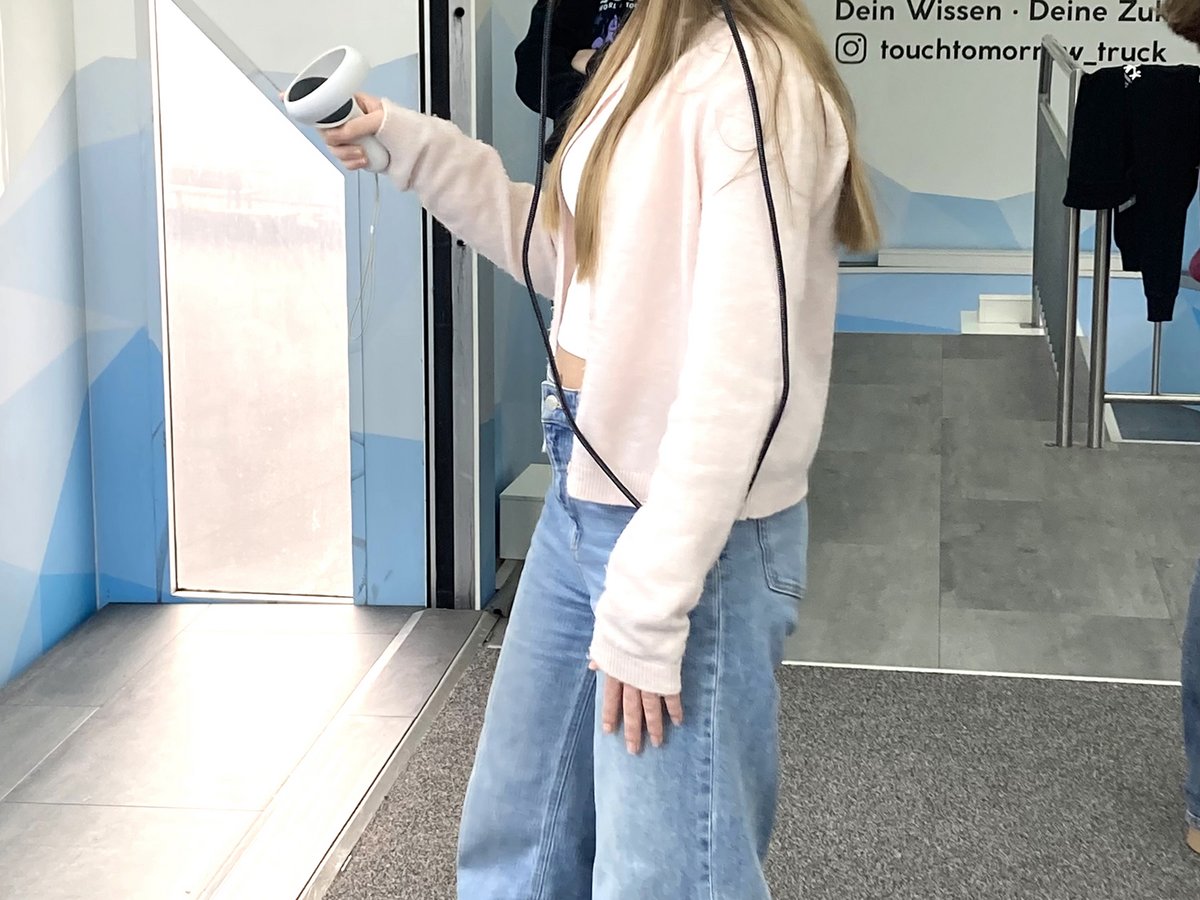 Junge Frau mit VR-Headset und Controller erkundet virtuelle Realität bei 'TOUCH TOMORROW'.