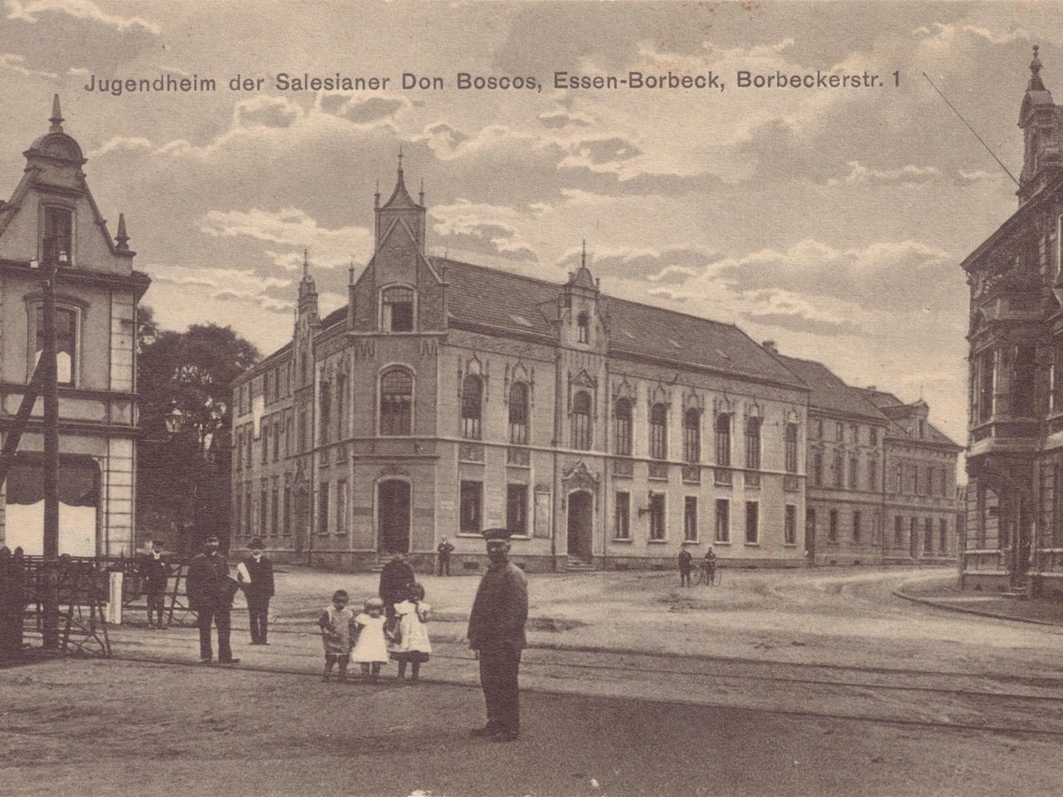 Historische Postkarte des Don Bosco Jugendheims in Essen-Borbeck, mit Personen und Straßenbahnschienen auf der Straße.