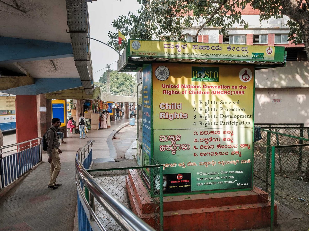 Ein Mann geht an einem gelben Schild vorbei, das die UN-Kinderrechte von 1989 und ein Zitat von Malala in Indien bewirbt.