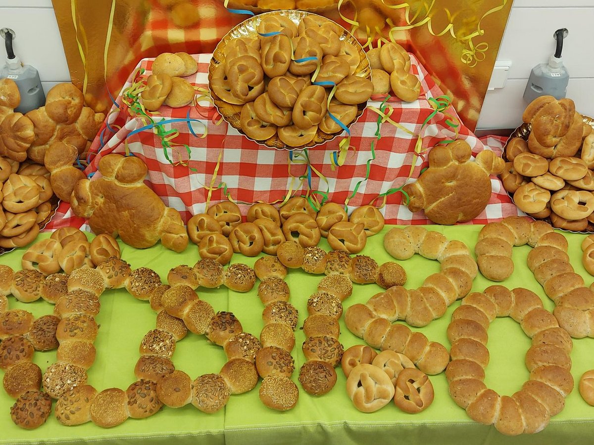Große Auswahl an Brötchen und Brezeln, teilweise zu 'HELLO' geformt, auf einem festlich gedeckten Tisch.
