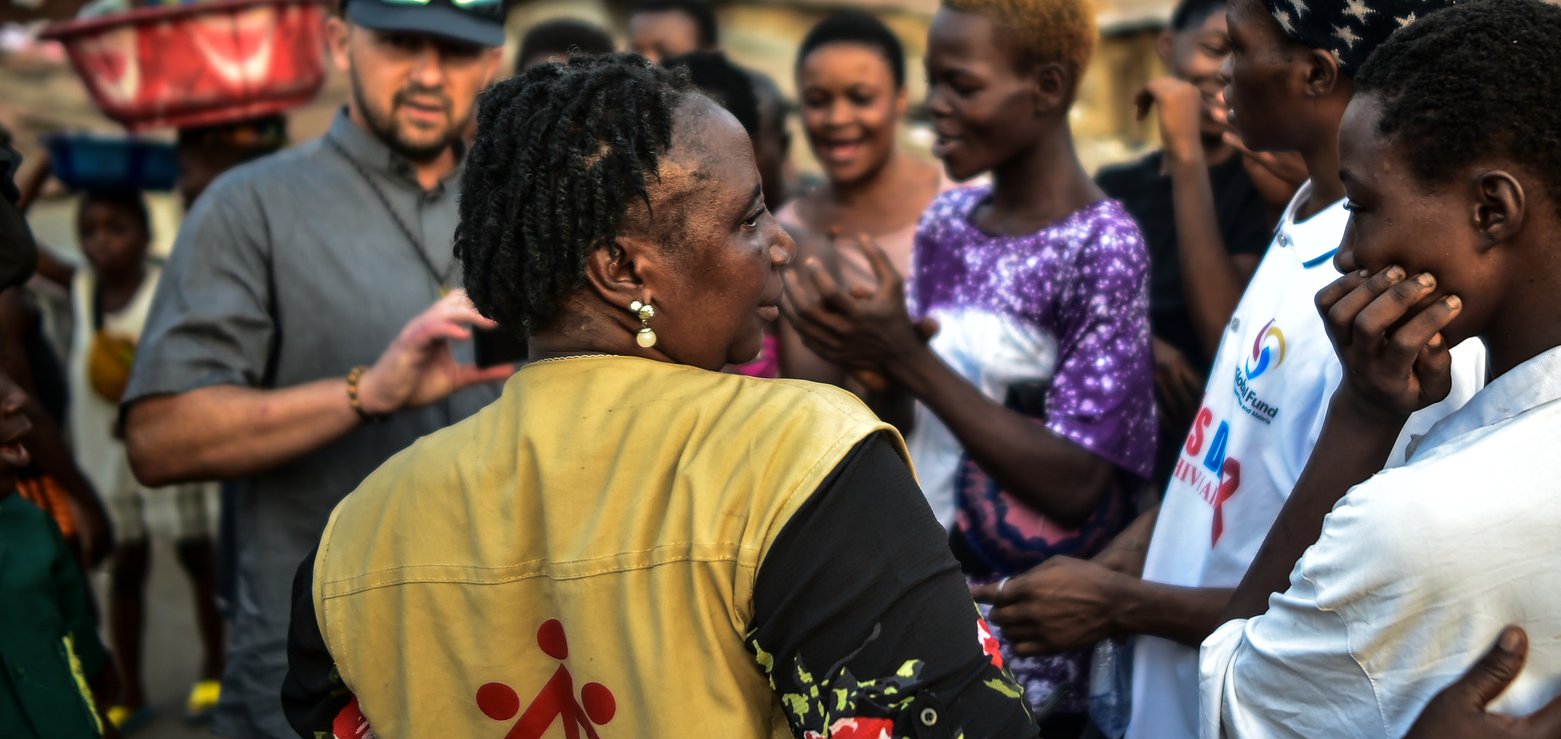 Don Bosco Helferin im Gespräch mit jungen Menschen in einer lebhaften, dicht besiedelten Gemeinde.