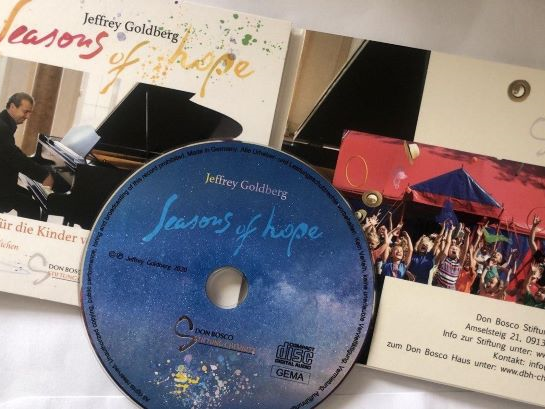 Eine CD 'Seasons of hope' von Jeffrey Goldberg, mit Booklet, das ihn am Klavier und jubelnde Kinder zeigt.