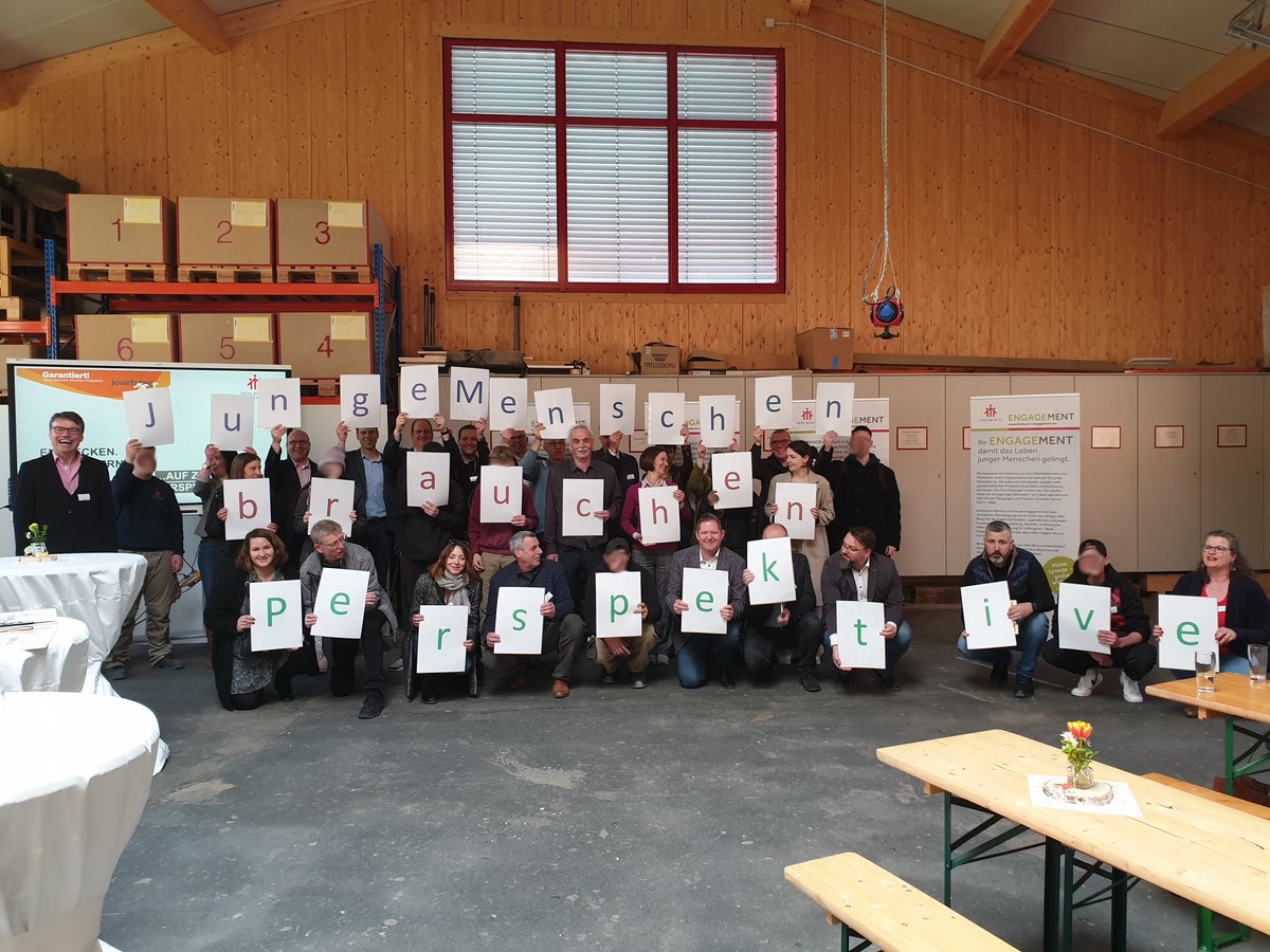 Eine Gruppe Menschen hält Schilder mit den Worten 'Junge Menschen brauchen Perspektive'.