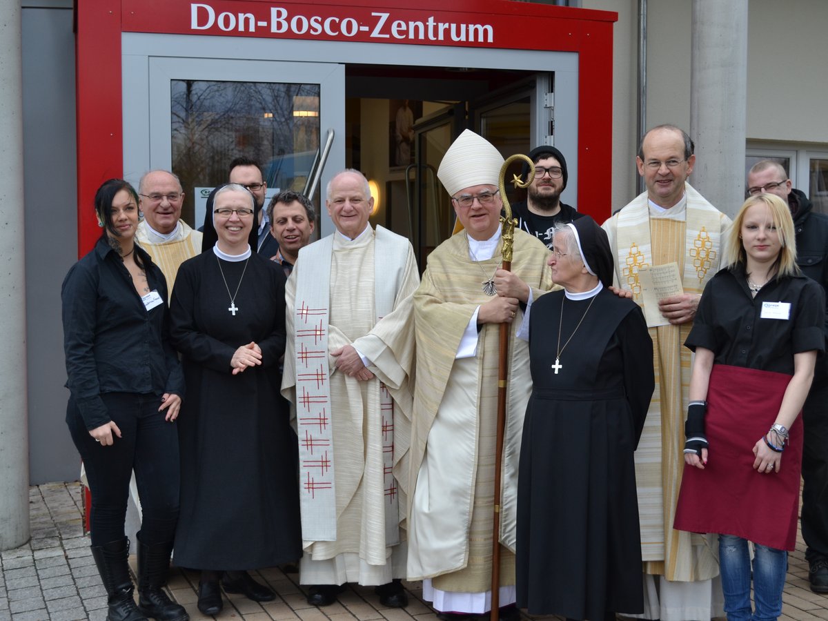 Ein Bischof, Priester, Nonnen und Laien posieren für ein Gruppenfoto vor dem Don-Bosco-Zentrum.