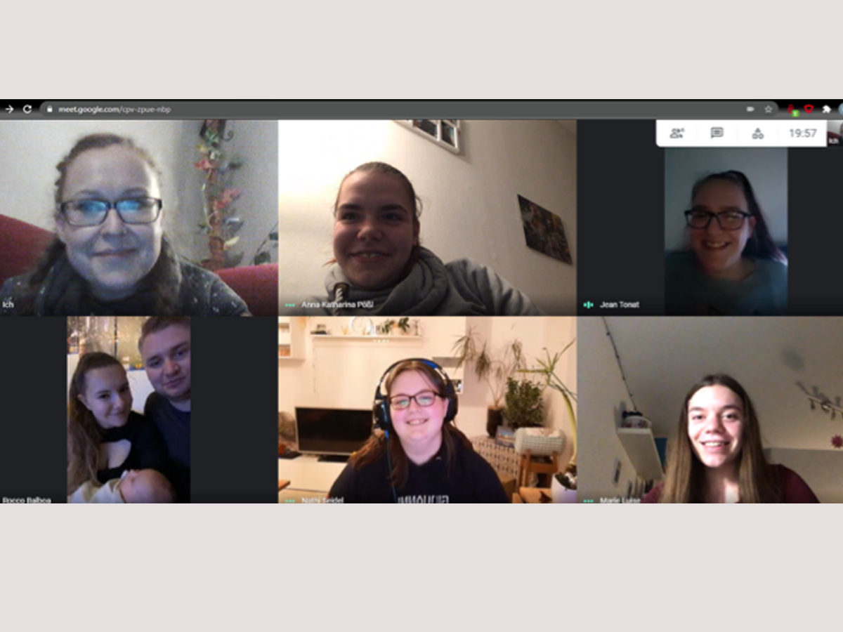 Ein Google Meet Videoanruf mit sechs lächelnden Teilnehmern in einem 3x2-Raster, darunter ein Paar mit Baby.