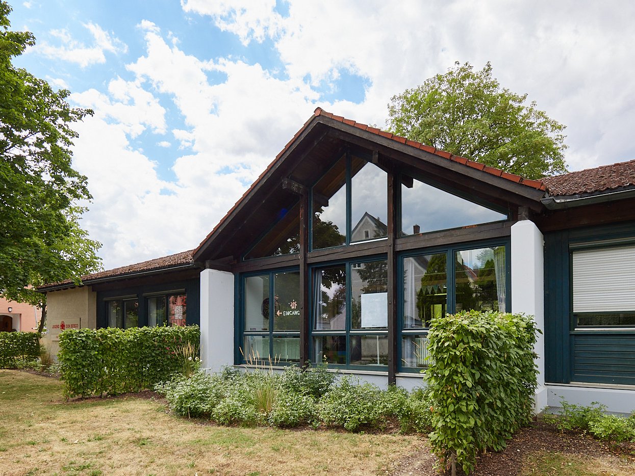 Haus mit Fenster grüne Wiese und Büschen