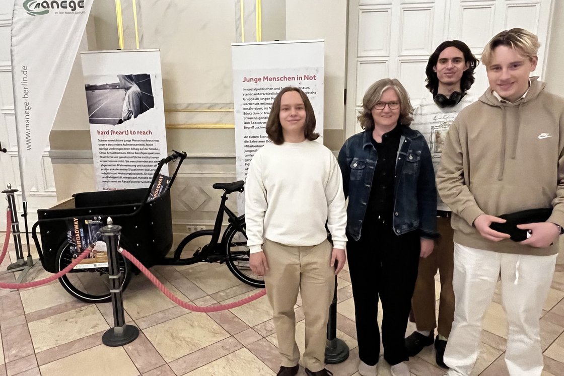 Gruppe von fünf Personen posiert mit Bannern und einem Lastenrad des Jugendhilfeprojekts 'manege-berlin'.