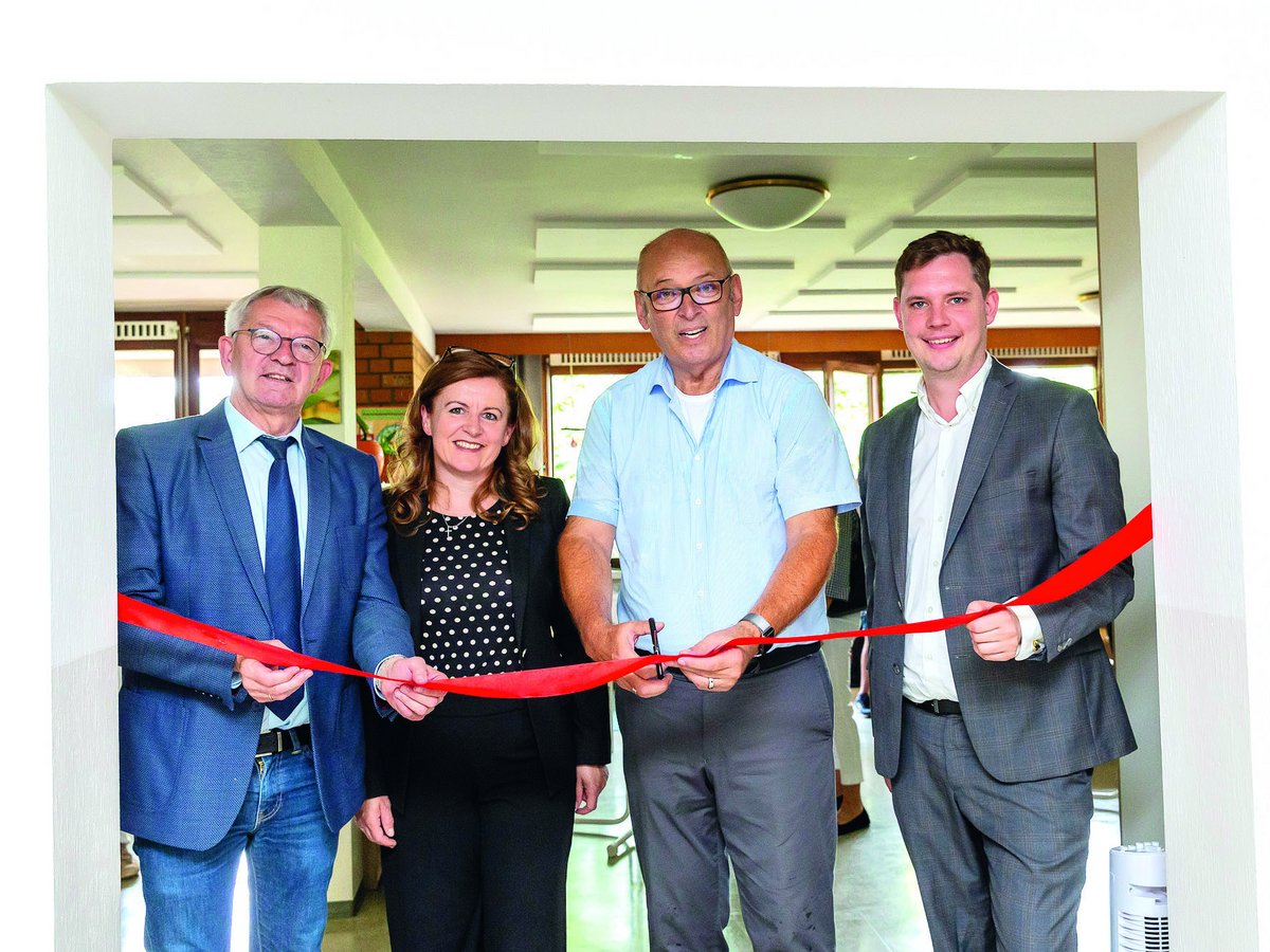 Vier lächelnde Personen, die bei einer Eröffnungsfeier ein rotes Band durchschneiden.