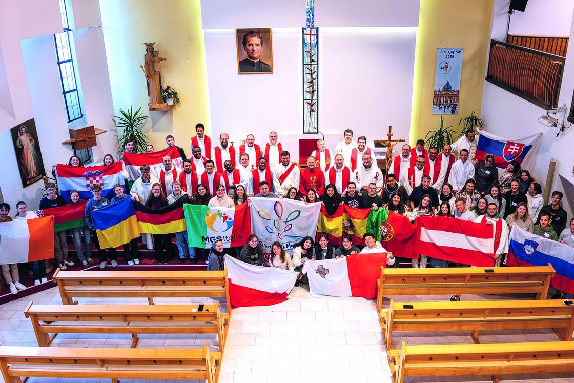 Junge Menschen und Geistliche mit Nationalflaggen aus vielen Ländern posieren in einer Kirche.