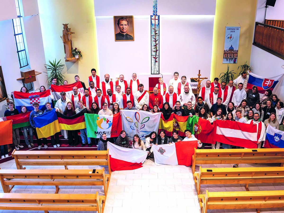 Junge Menschen und Geistliche mit Nationalflaggen aus vielen Ländern posieren in einer Kirche.