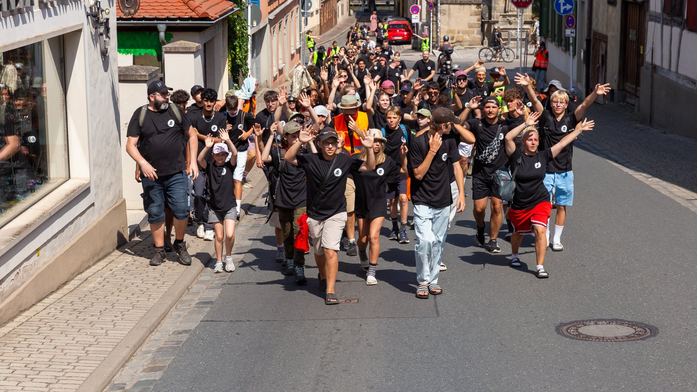 Große Gruppe Jugendlicher fröhlich auf Straße unterwegs