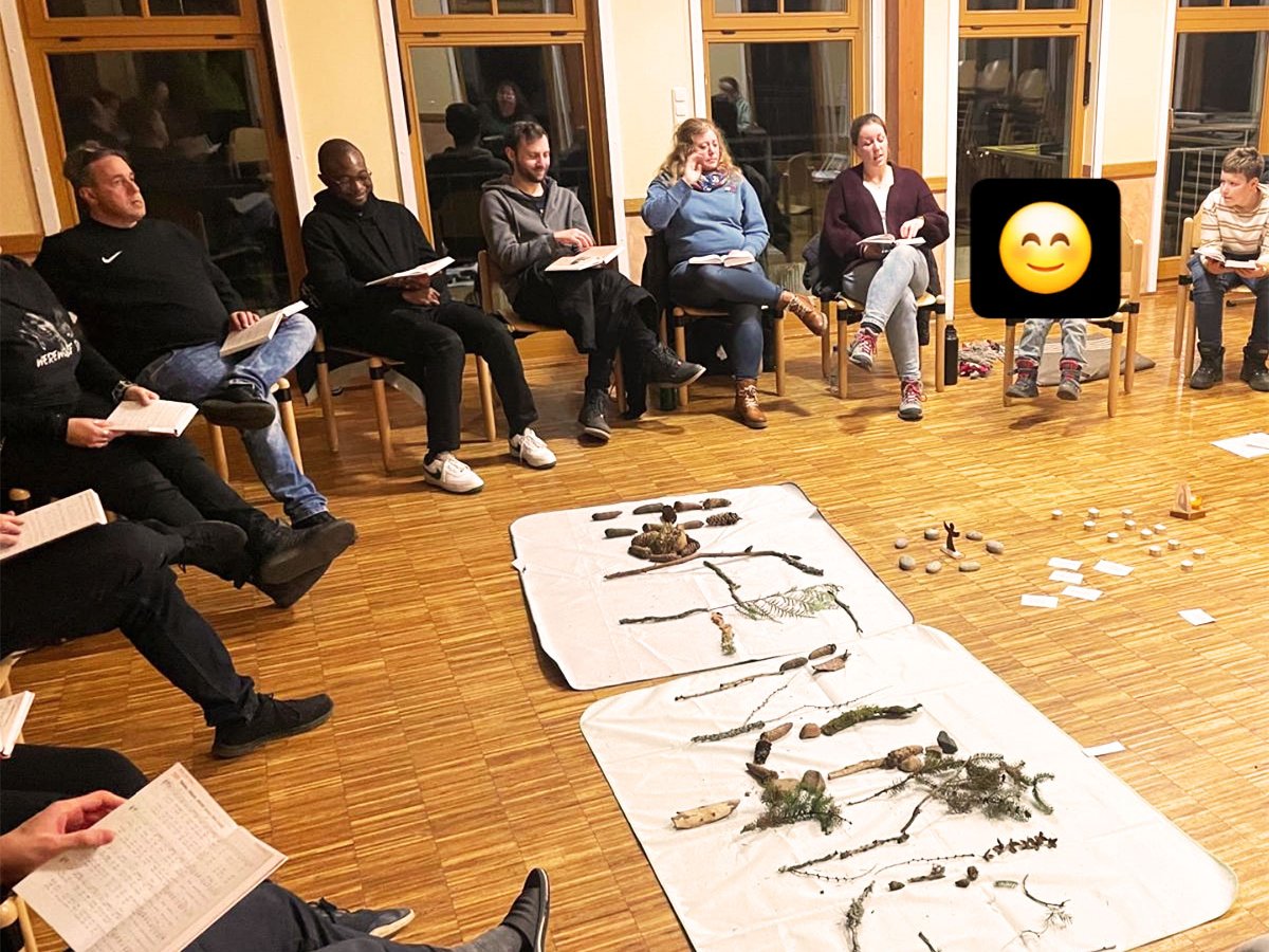 Eine Gruppe von Personen in einem Raum, die natürliche Materialien auf Bodentüchern während eines Workshops betrachten.