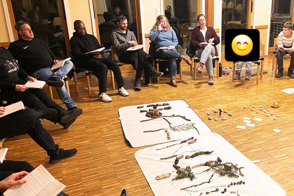Eine Gruppe von Personen in einem Raum, die natürliche Materialien auf Bodentüchern während eines Workshops betrachten.