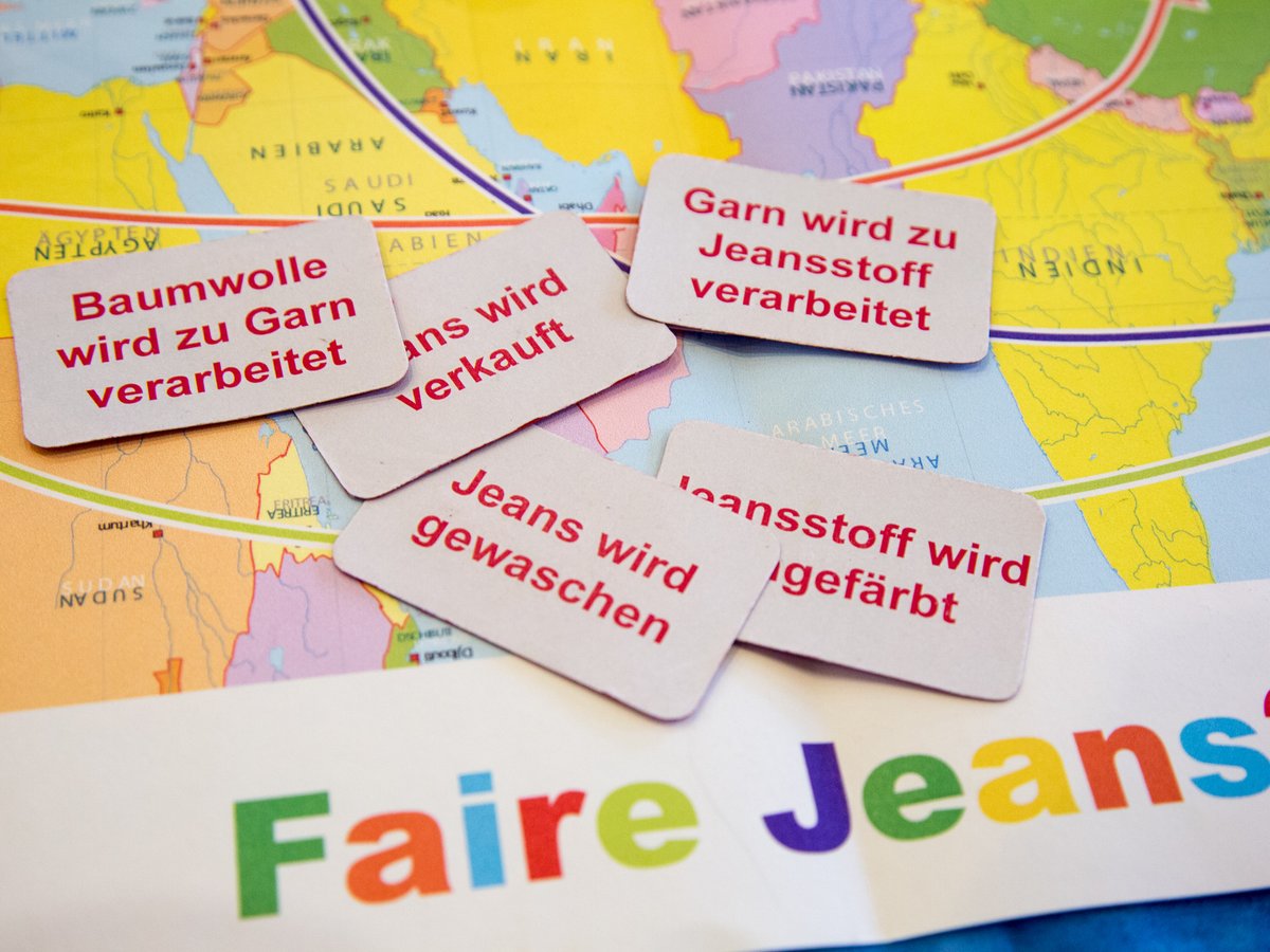 Karten auf Weltkarte zeigen Jeansproduktion (Baumwolle, Garn, Färben, Waschen). Die Frage "Faire Jeans?" ist gestellt.