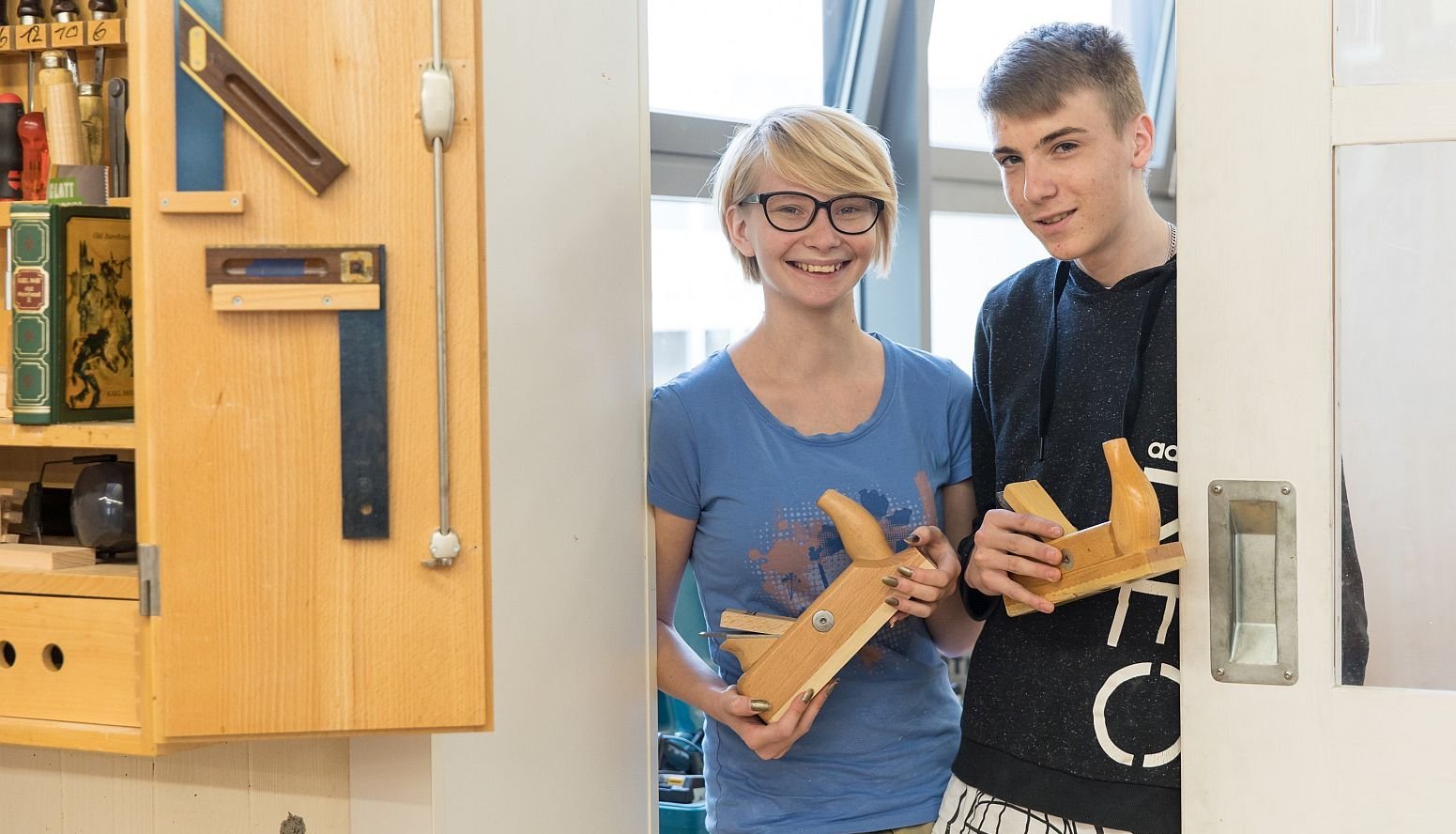 Zwei Jugendliche stehen in einem Türrahmen und lächeln.