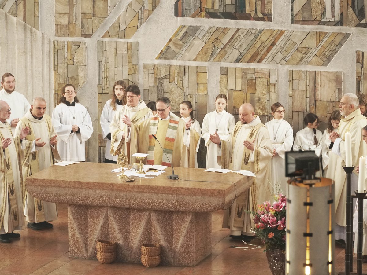 Priester und Messdiener halten einen Gottesdienst in einer Kirche ab, versammelt um einen steinernen Altar.