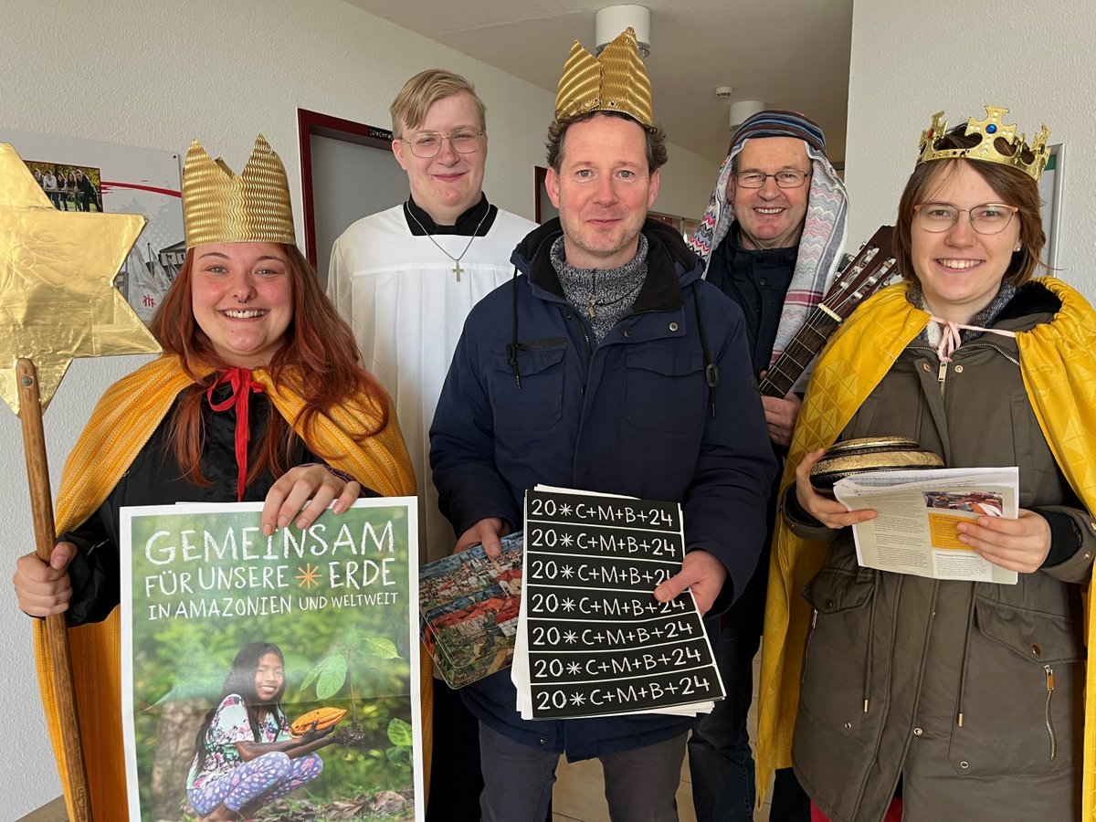 Fünf Sternsinger, drei als Könige verkleidet, einer im Messdienergewand, werben für die Spendenaktion 'GEMEINSAM FÜR UNSERE ERDE'.