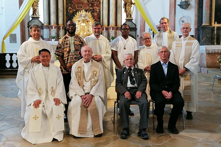Diverse Priester und Männer verschiedener Altersgruppen in einer Kirche.