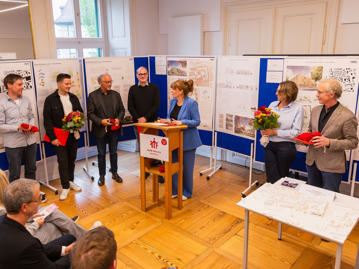 Preisverleihung eines Architekturwettbewerbs bei Don Bosco Bamberg, Teilnehmer präsentieren Schulbaupläne und erhalten Auszeichnungen.