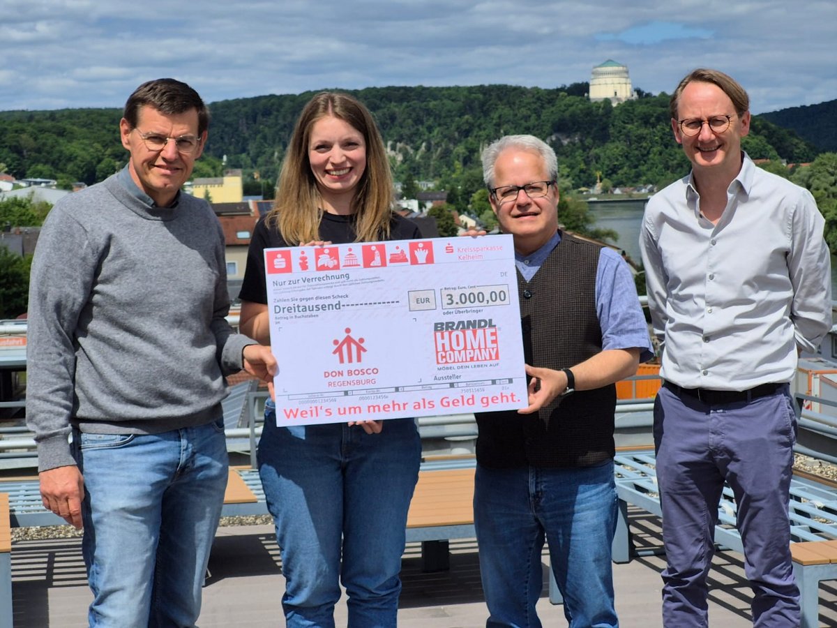 Vier lächelnde Personen mit einem großen Scheck über 3.000 EUR an Don Bosco Regensburg von Brandl Home Company.