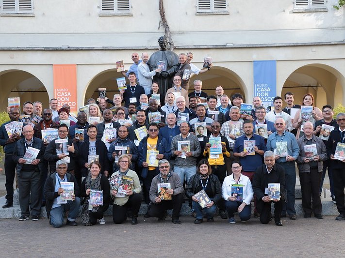 Vielfältige Gruppe lächelt, hält Bücher und Zeitschriften vor dem Museo Casa Don Bosco.
