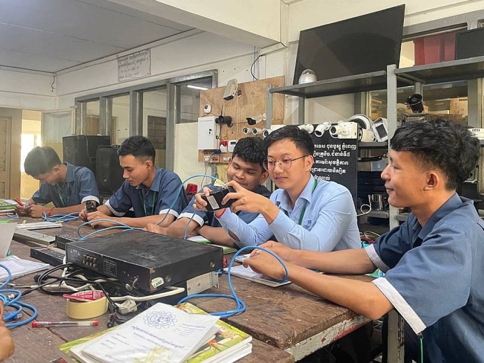 Berufsschüler lernen Elektronik und Netzwerktechnik mit einem Lehrer in einem praktischen Workshop.