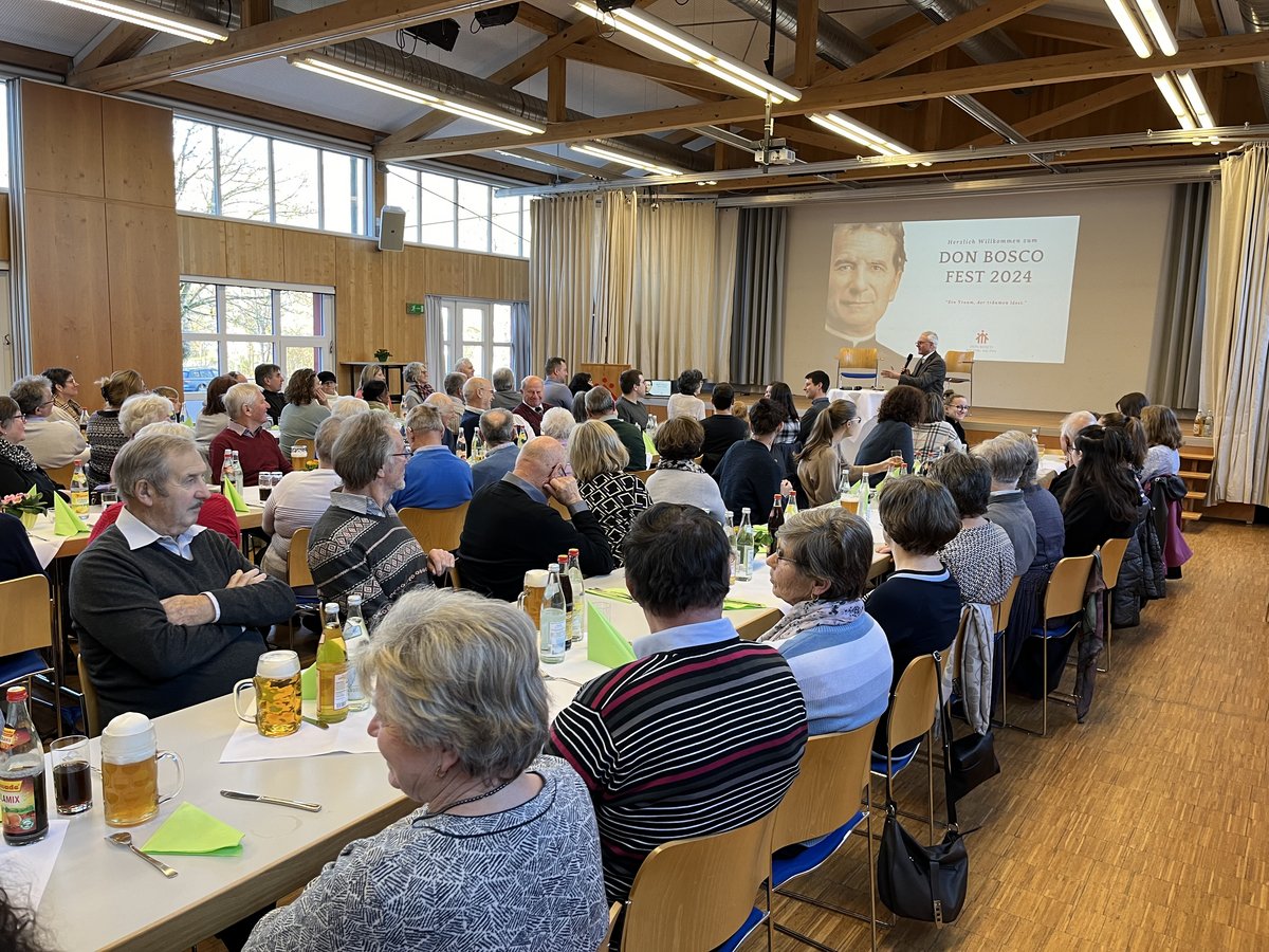 Besucher des Don Bosco Fest 2024 in einem Saal, die einem Redner und einer Projektionswand zusehen.