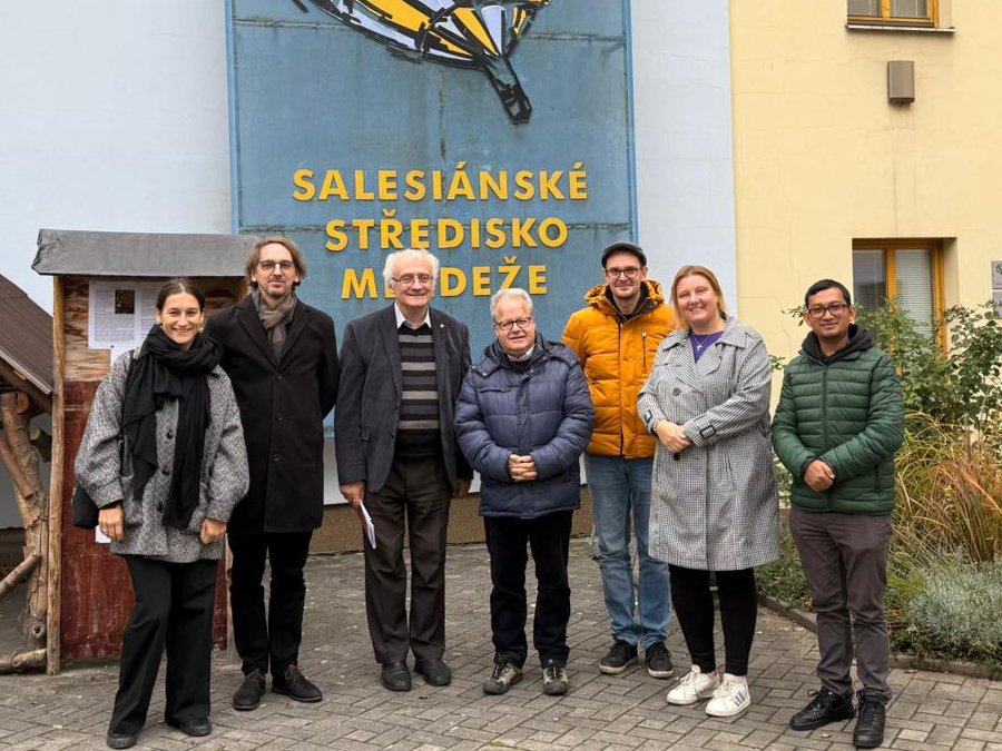 Sieben Personen unterschiedlichen Alters, darunter Männer und Frauen, lächeln vor dem Salesianischen Jugendzentrum.