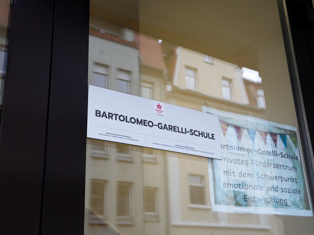 Schild der Bartolomeo-Garelli-Schule, einem privaten Don Bosco Förderzentrum für emotionale und soziale Entwicklung, im Fenster.