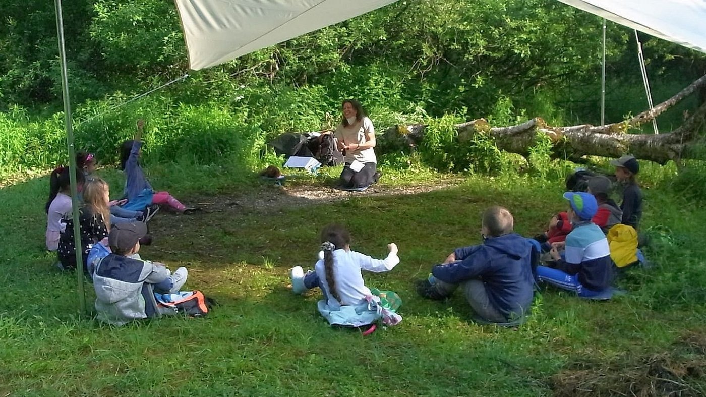 Menscheen sitzen unter einer Zeltplane und lachen.