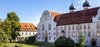 Ansicht Kloster seitlich mit Bäumen und Kirchtürmen im Hintergrund