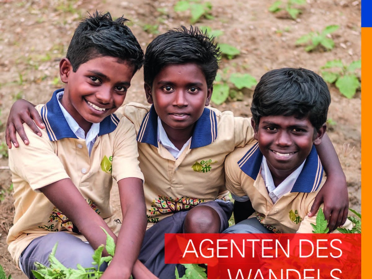 Drei lächelnde Jungen in beigen Poloshirts sitzen im Garten und präsentieren grüne Tomaten. Sie symbolisieren 'Agenten des Wandels'.
