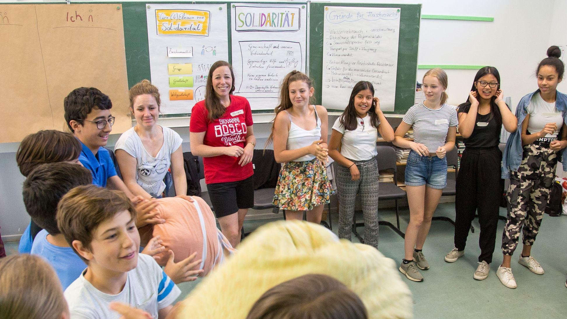 Diverse Jugendliche und Erwachsene in einem Klassenzimmer, bilden einen Kreis für einen interaktiven Workshop zu Solidarität.