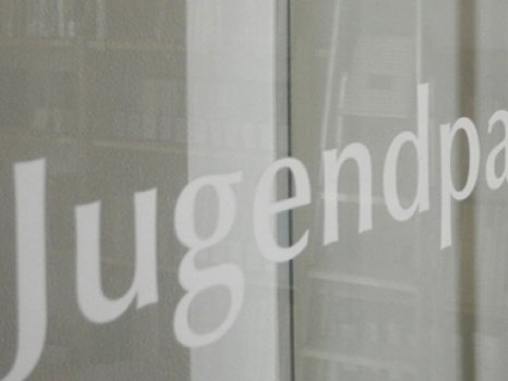 Die Schrift "Jugendpastoralinstitut" auf einer Glastür, dahinter und rechts davon Bücherregale.