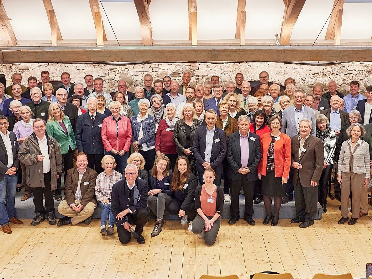 Eine große Menschenmenge steht in einem Zelt und lächelt in die Kamera.