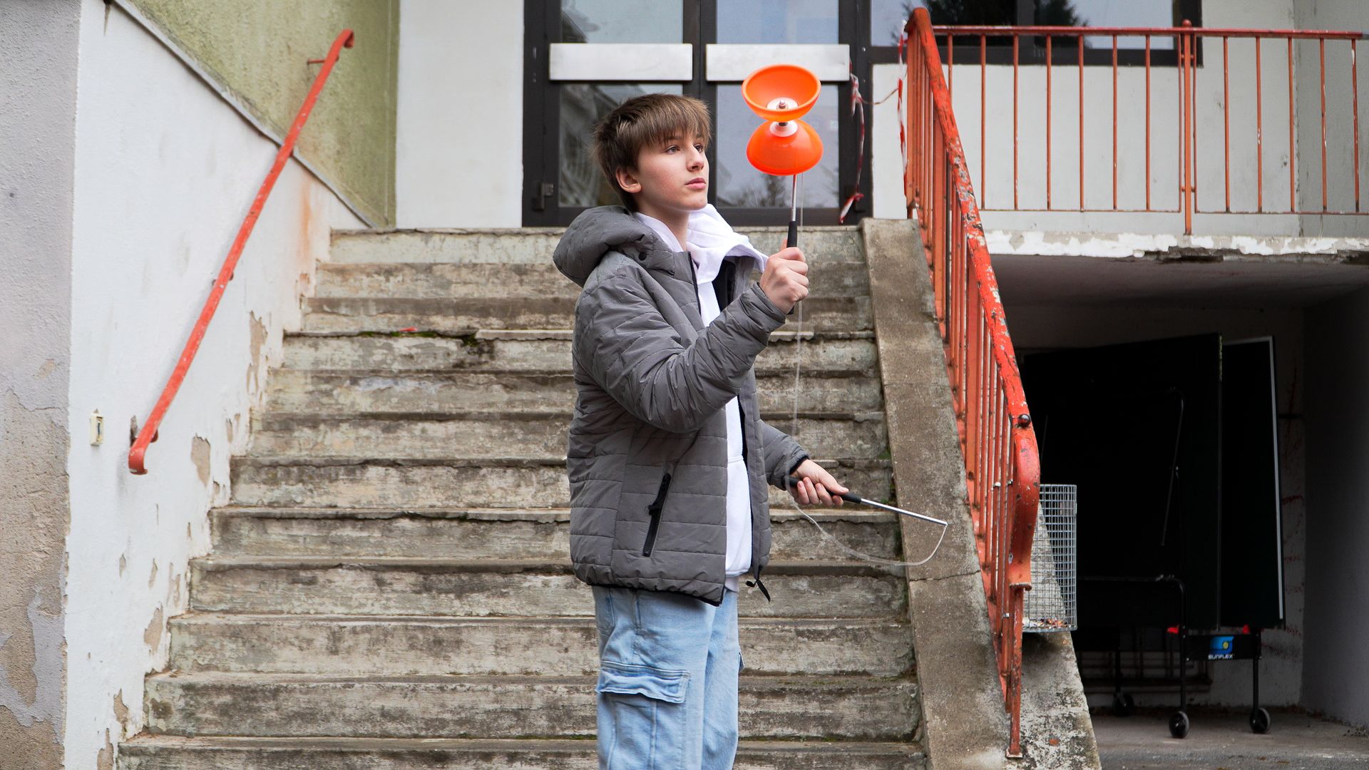 Ein Junge spielt vor einer Treppe mit einem Diabolo.