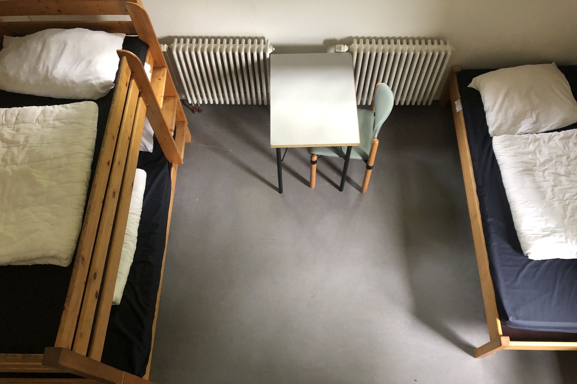 Zimmer von oben fotografiert mit Stockbett, Tisch, Stuhl und Einzelbett